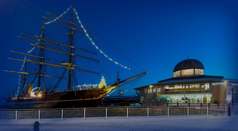 The Royal Research Ship Discovery and the associated octagonal museum building pictured at Discovery Point Dundee by night.